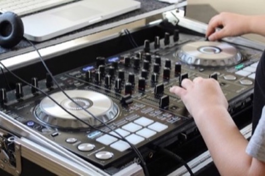 A student uses professional DJ equipment to mix tracks