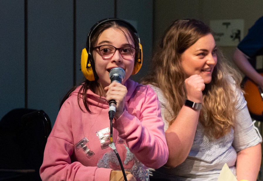 A photo of happy young person holding a microphone, staring directly into the camera.  
