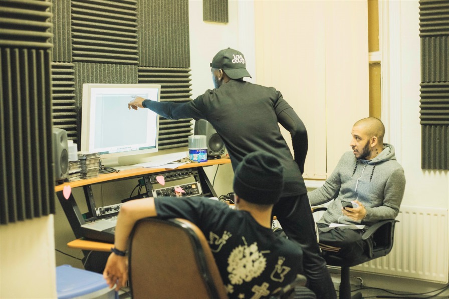 Three young people working on music on a computer