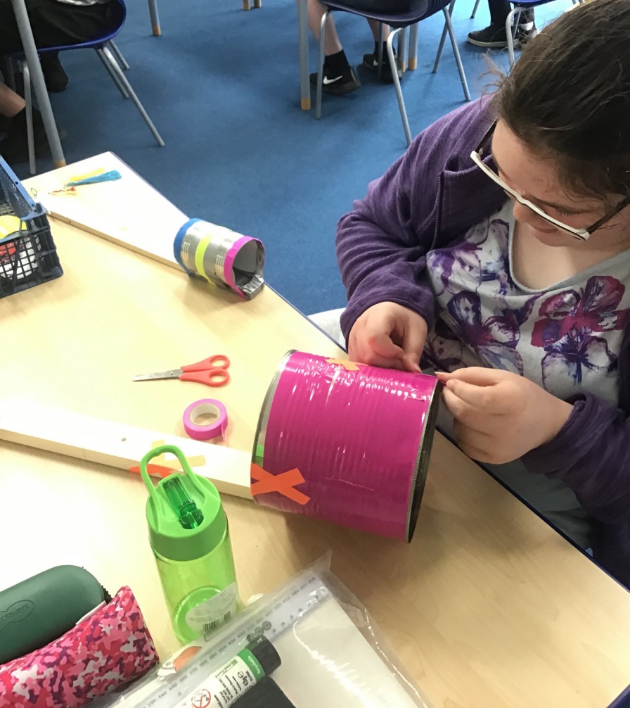 SEN pupil making a homemade instrument with a food can