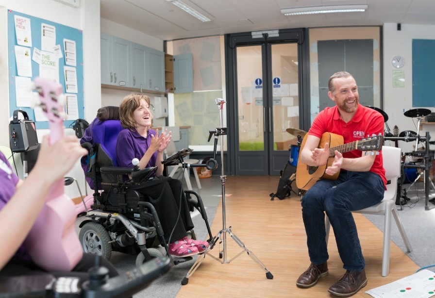 Young disabled musician and music leader smiling and clapping in a music session