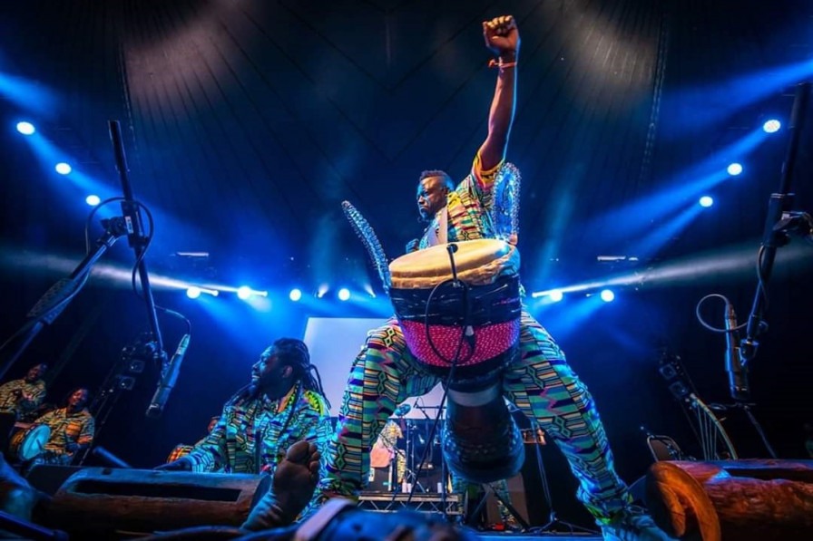 Drummer Sidiki Dembele with his arm up in the arm wearing a drum
