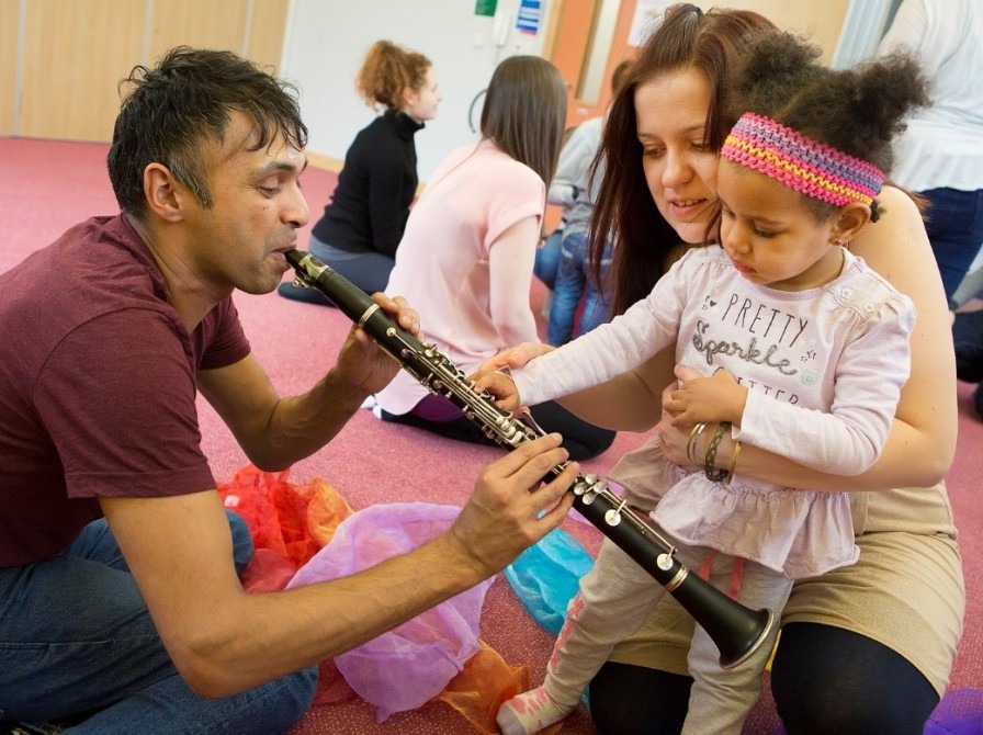 Child learning about an instrument surrounded by adults