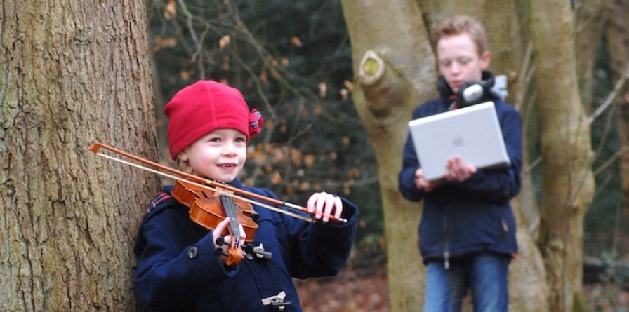 A girl plays the violin in a woodland