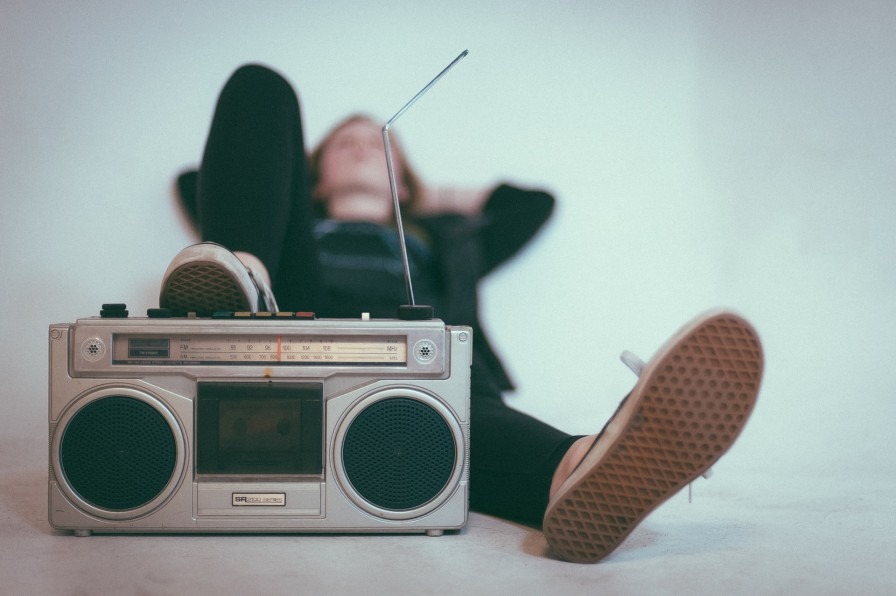A teenager laying with an old fashioned silver boombox