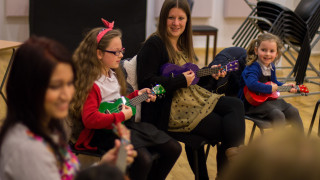 Children and adults playing ukuleles
